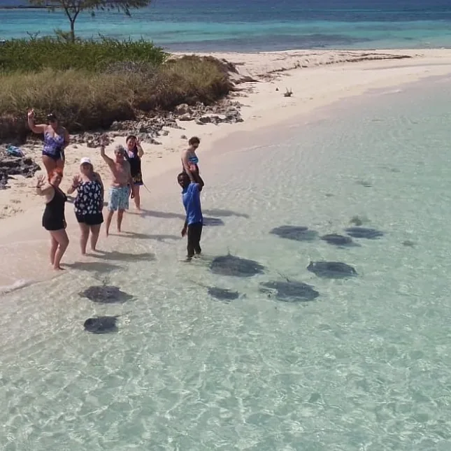 Visitors standing in shallow clear water at Honeymoon Harbour in Bimini