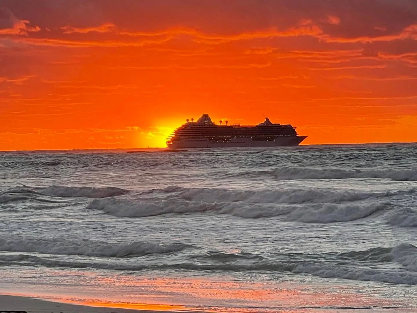 Deep orange sunset over the ocean off Bimini with a ship on the horizon