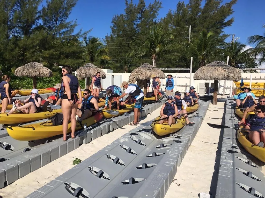 Rows of yellow kayaks lined up on a launch ramp with a group getting ready