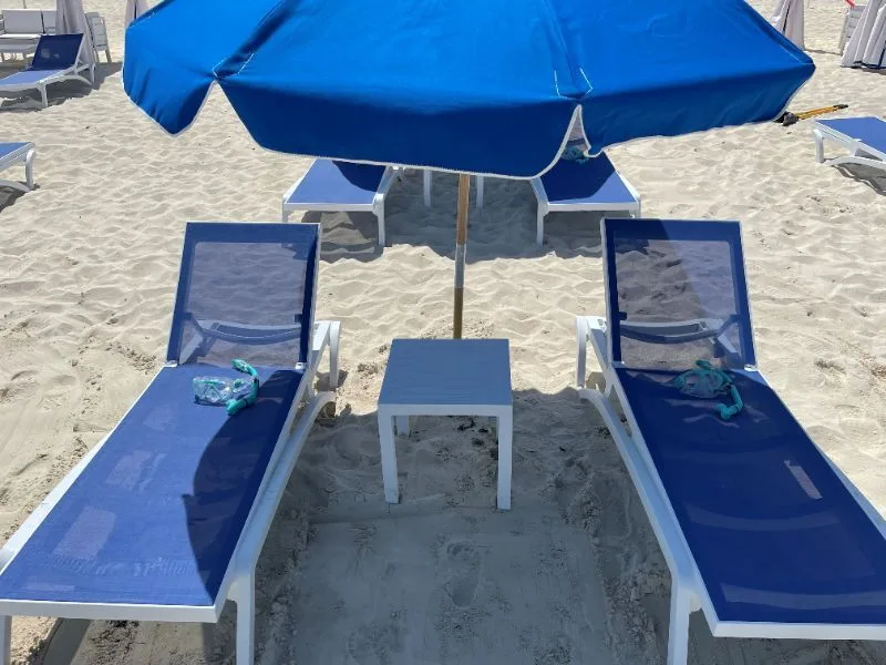 Two blue loungers and an umbrella set up on the white sand at Bimini