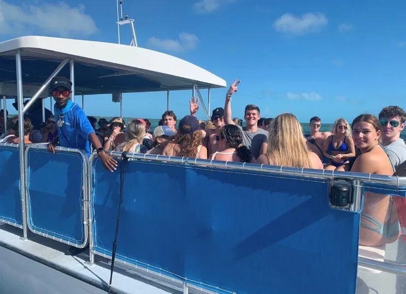 Guests aboard a covered Bimini Blue Adventures charter boat on turquoise water